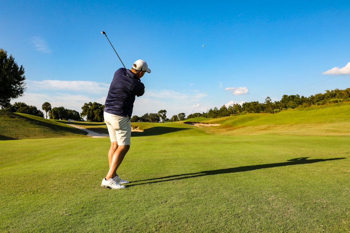 Golfer in mid-swing on a sunny golf course